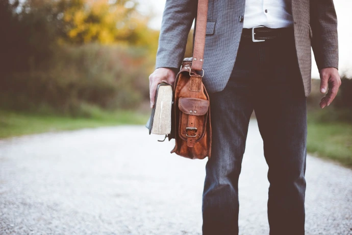 un homme qui marche avec un livre et sa malette de travail